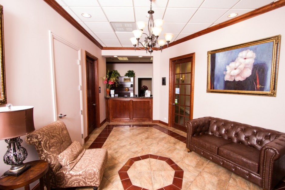 Waiting area of a professional office with a brown leather couch, a wooden coffee table, and a framed picture on the wall.