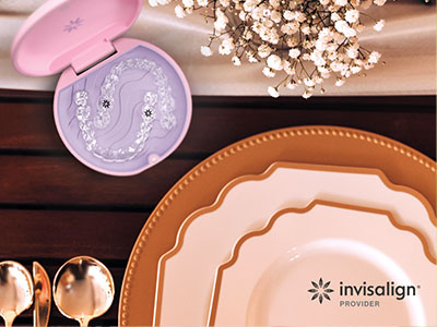 The image shows a collection of tableware, including plates and a box with a toothbrush inside, displayed on a table against a background that includes a pink object, a wooden surface, and a decorative arrangement.