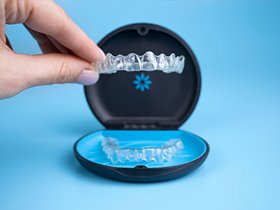 A person s hand holding a blue and black dental impression kit with the lid open.