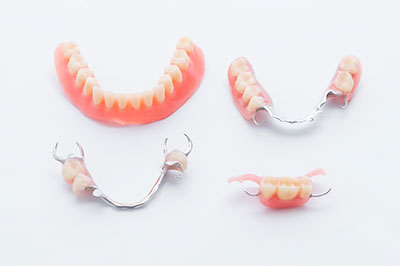 The image shows a set of dental braces with pink teeth and silver clasps, displayed against a white background.