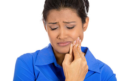 The image shows a woman with her mouth open, appearing to be in distress or pain. She is holding her face and looking upwards with an expression of concern.