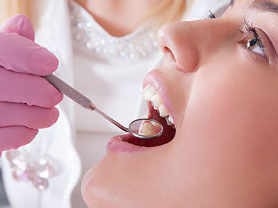 A dental professional is performing a teeth cleaning procedure on a patient using specialized dental tools.