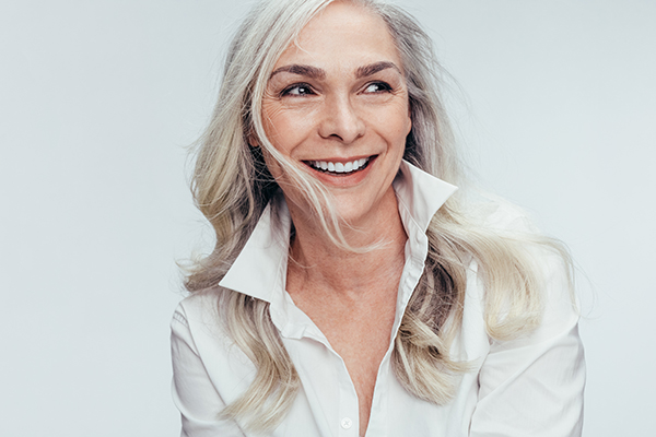 A woman with blonde hair and a white shirt, smiling at the camera.